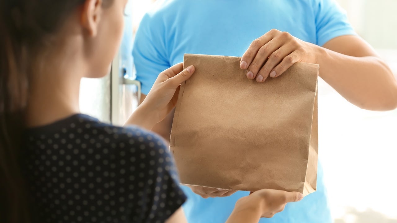 un chauffeur de Doordash livre un repas à un client|Un client reçoit son repas depuis Doordash