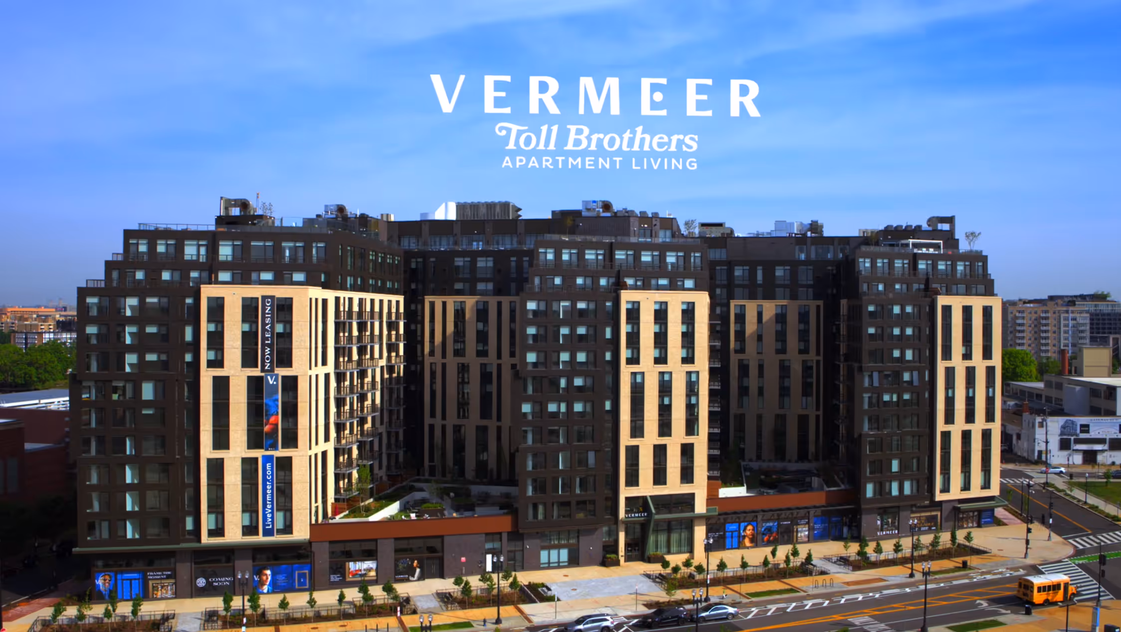 Vermeer by Toll Brothers Apartment Living, a modern luxury apartment complex with mixed-use retail on the ground floor, located on a busy city street.