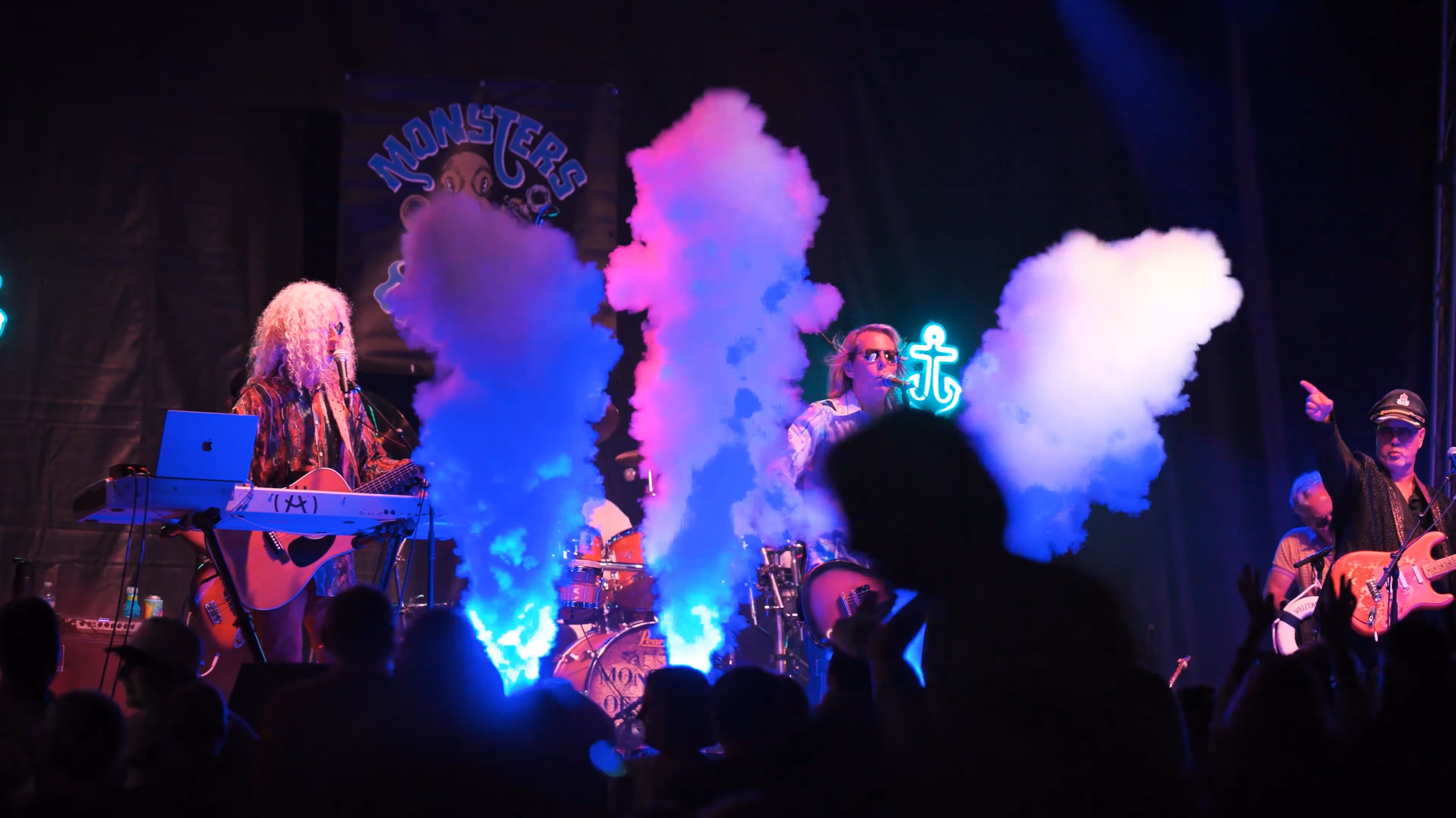 Porchfest event with band on stage & smoke shooting from the ground around people 