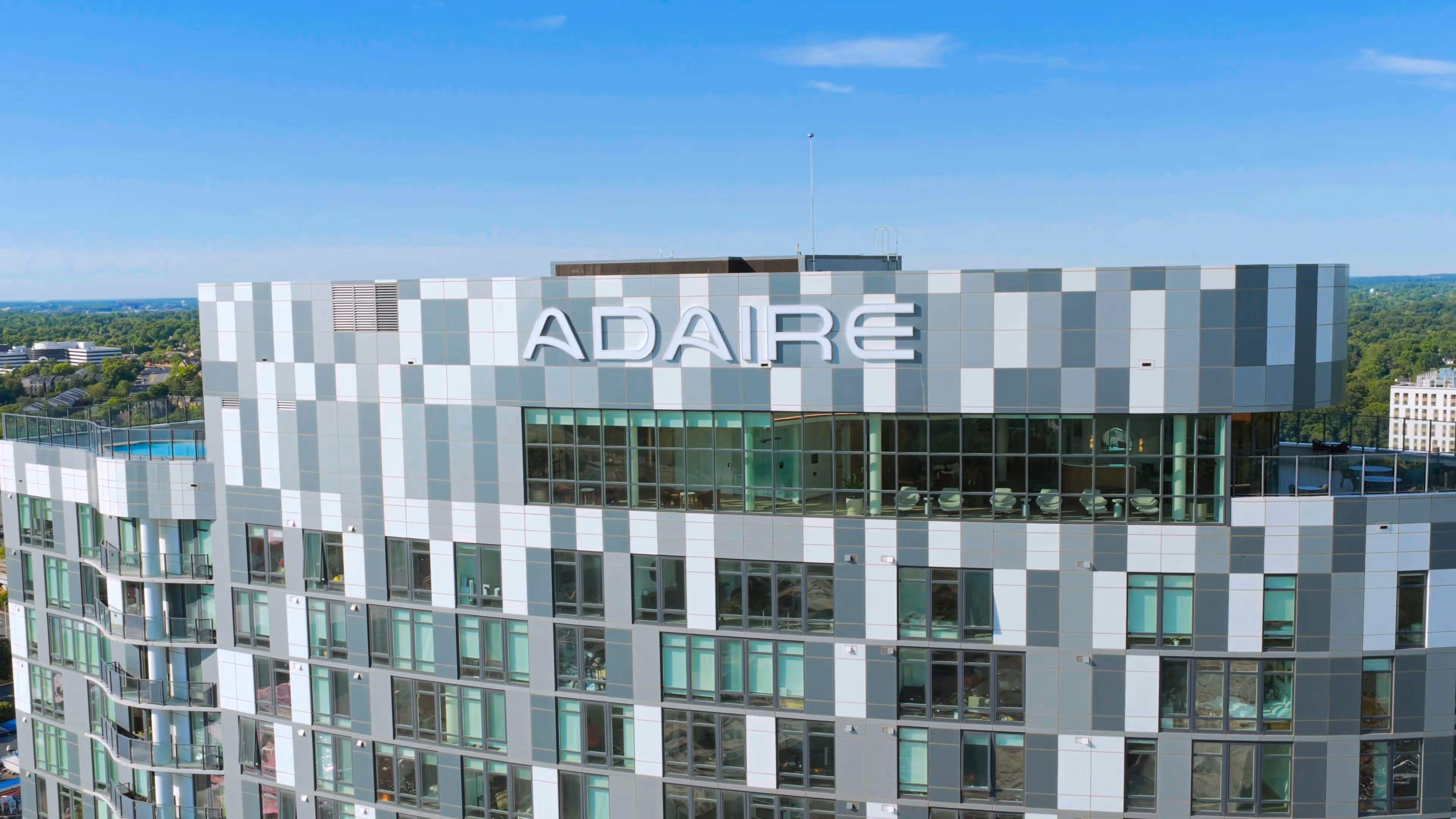 Modern high-rise building with ADAIRE sign on top, featuring glass windows and balconies.