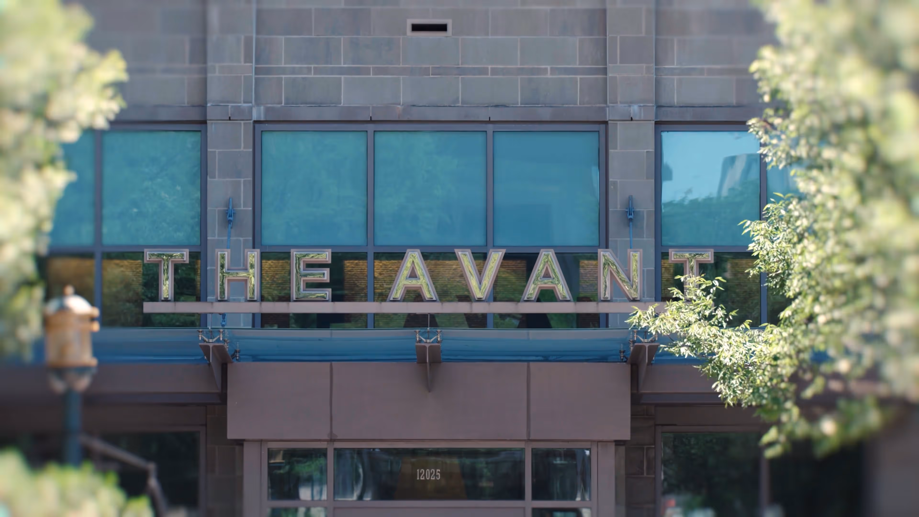 Building entrance with large windows and a sign reading 'THE AVANT' above the door.