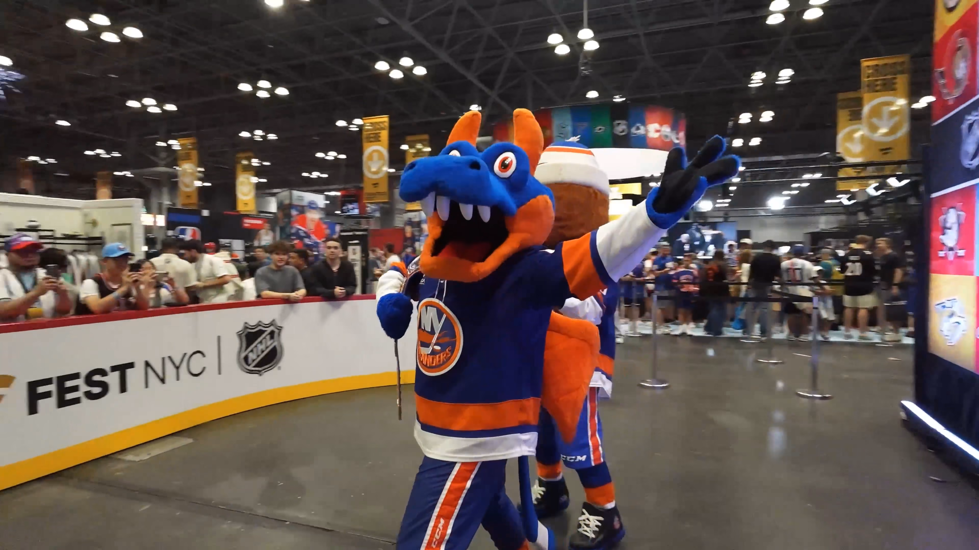 New York Islanders mascot in hockey jersey posing with fans at an indoor NHL event in NYC.