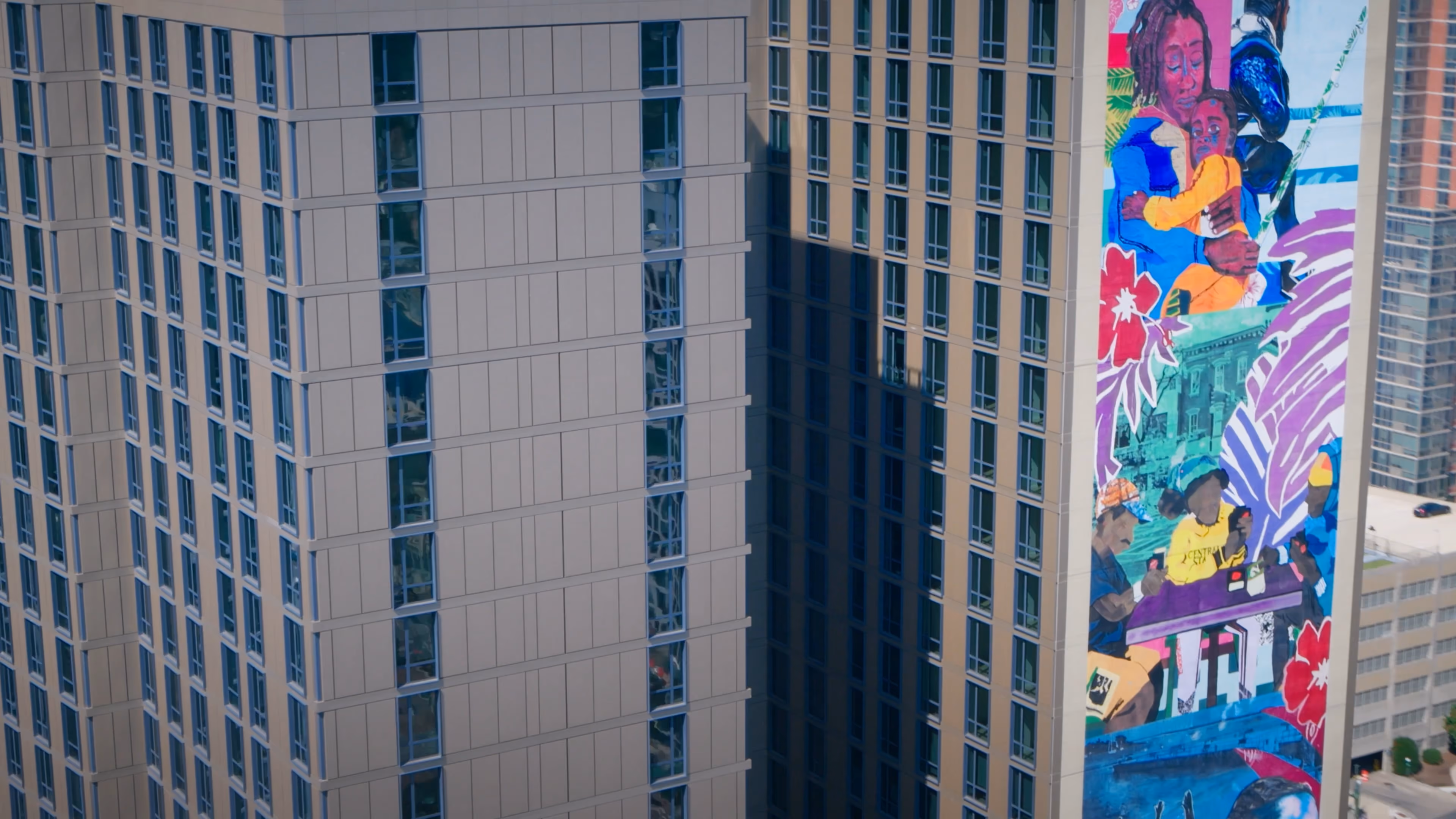 Tall building with colorful mural showing people interacting and embracing on the side.
