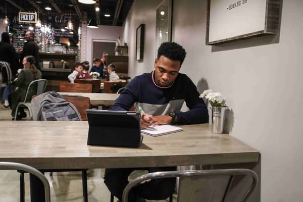 A man writing notes in a busy coffee shop