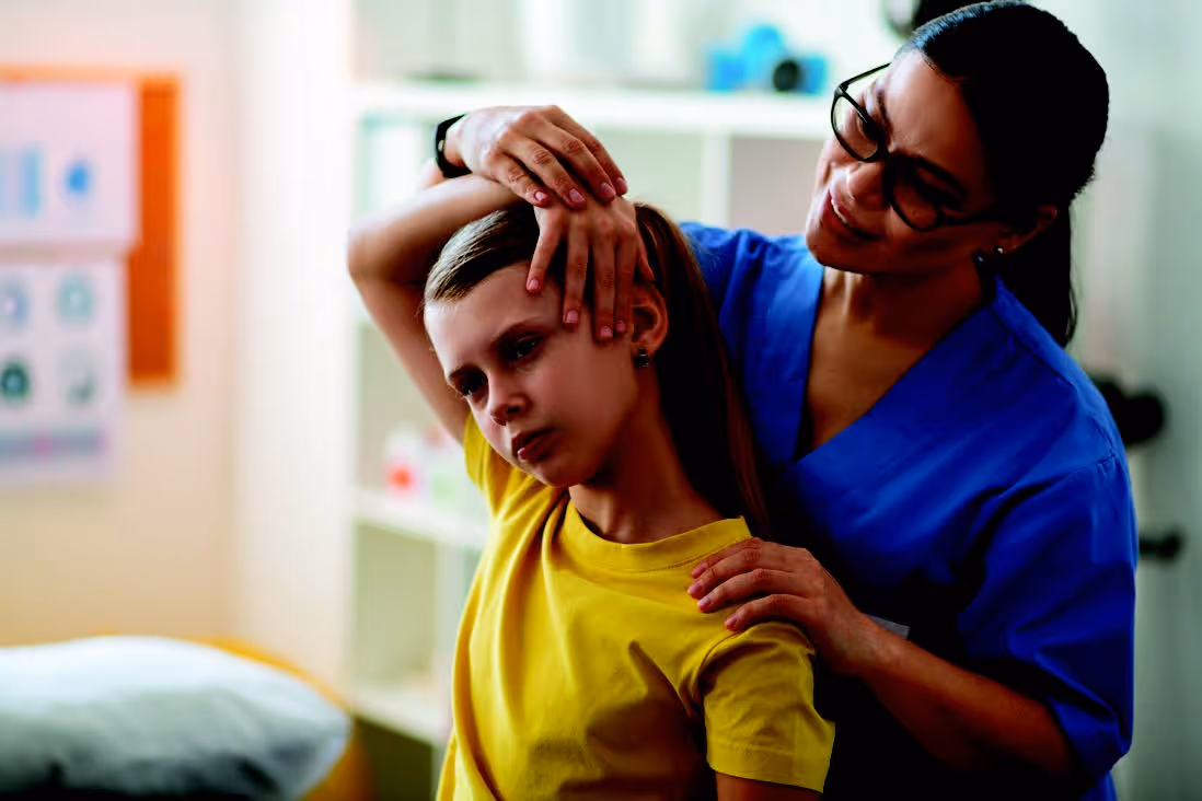 Female nurse helping young girl with neck exercises