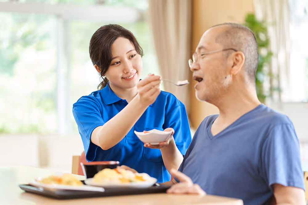 Young Asian nurse feeding disabled man 