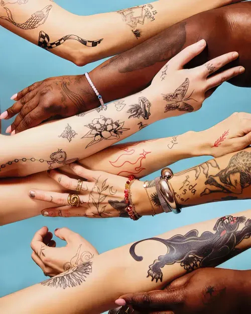 Une photo studio avec plusieurs personnes tendant leur bras recouverts de tatouages