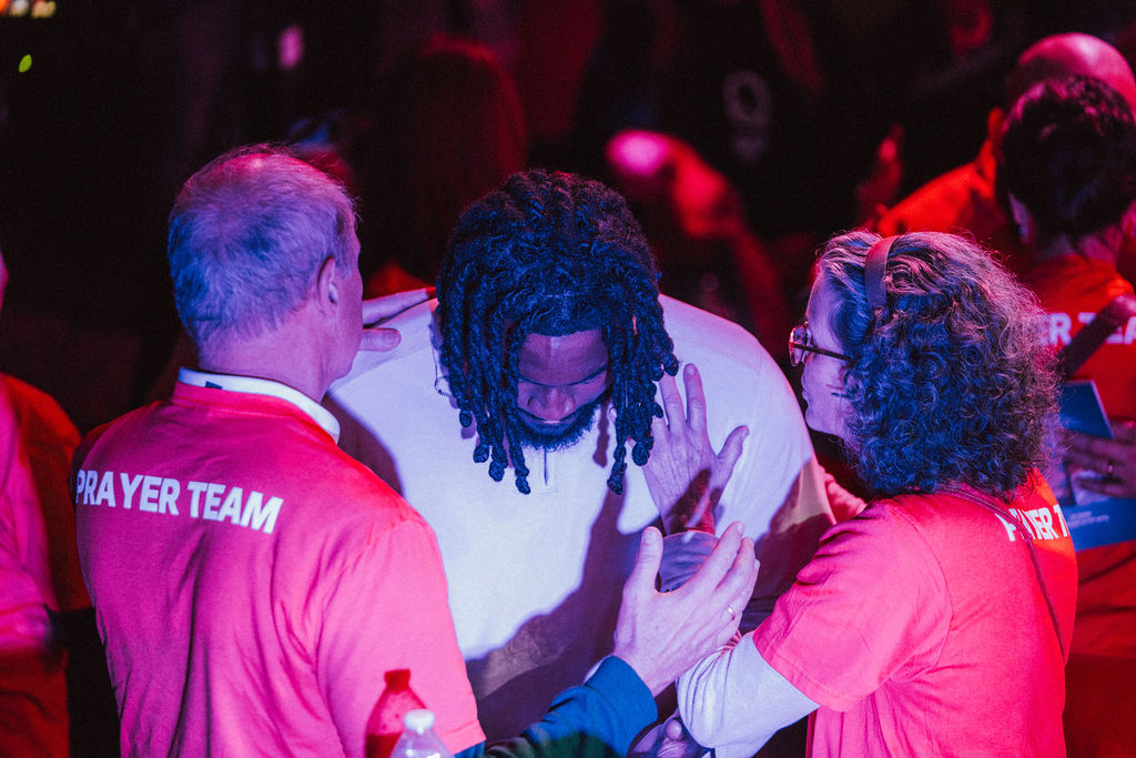 Man being covered in prayer by prayer team.