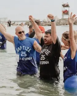 Large outdoor baptism event with crowds near water representing the global Baptize the World movement after California revival
