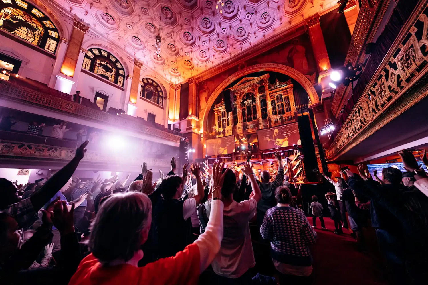 Packed congregation with hands raised in worship inside Tremont Temple at AWAKE America Boston rally