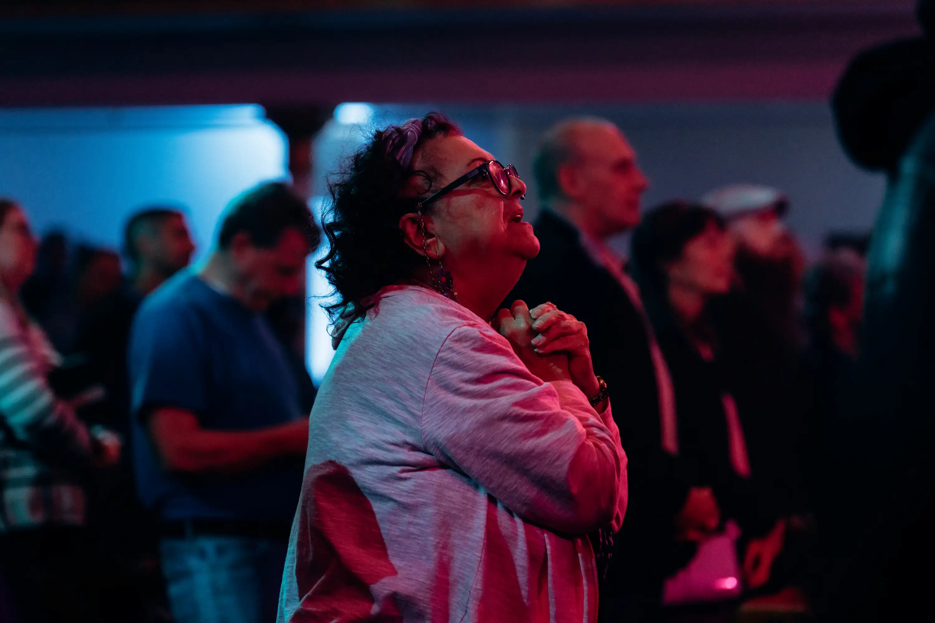 Woman praying with clasped hands looking upward at AWAKE America Boston rally