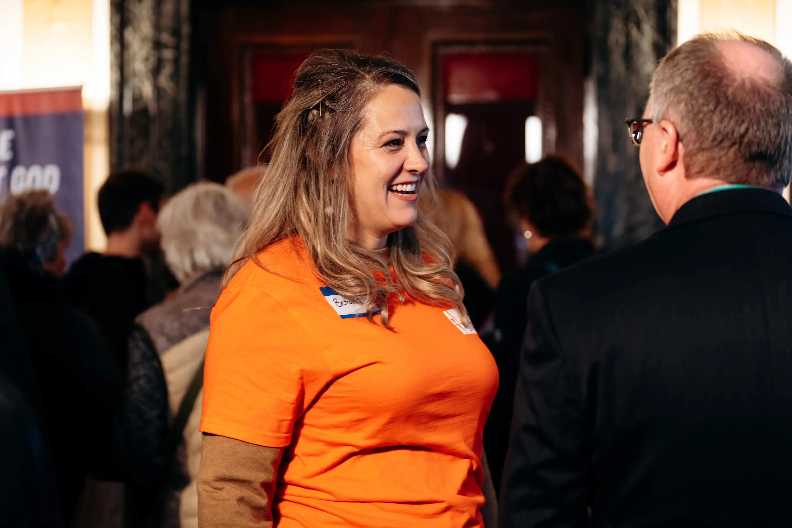 AWAKE America volunteer in orange shirt greeting attendees at Boston rally