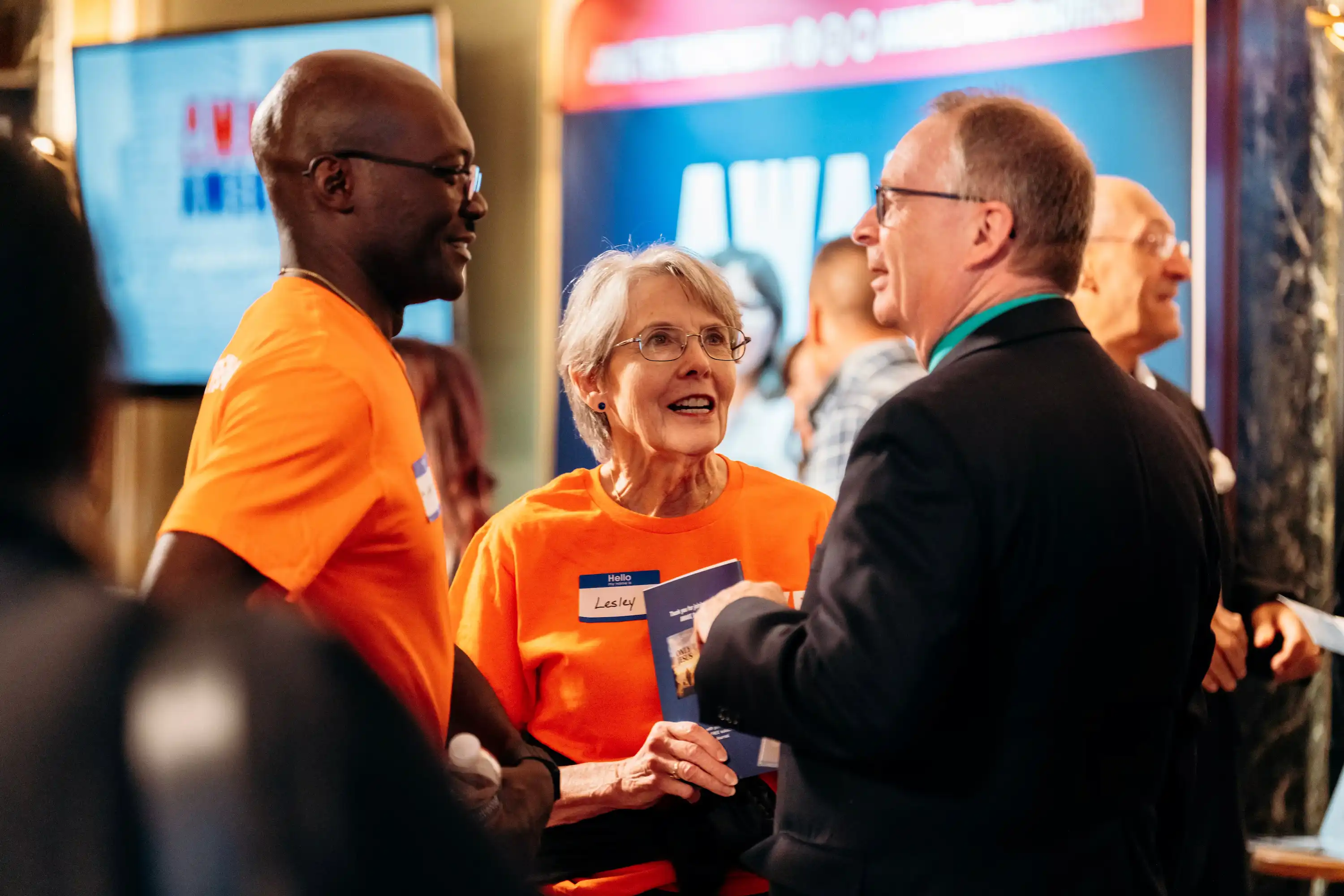 AWAKE America volunteers in orange shirts greeting a guest at Boston rally