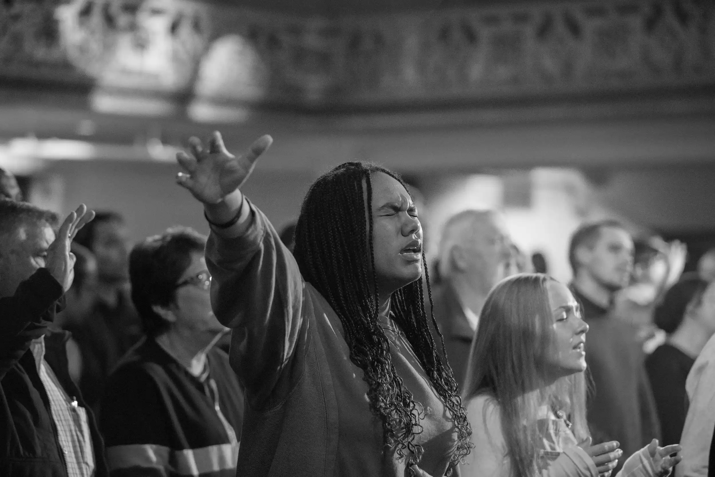 Woman raising her hand in worship at AWAKE America Boston rally at Tremont Temple