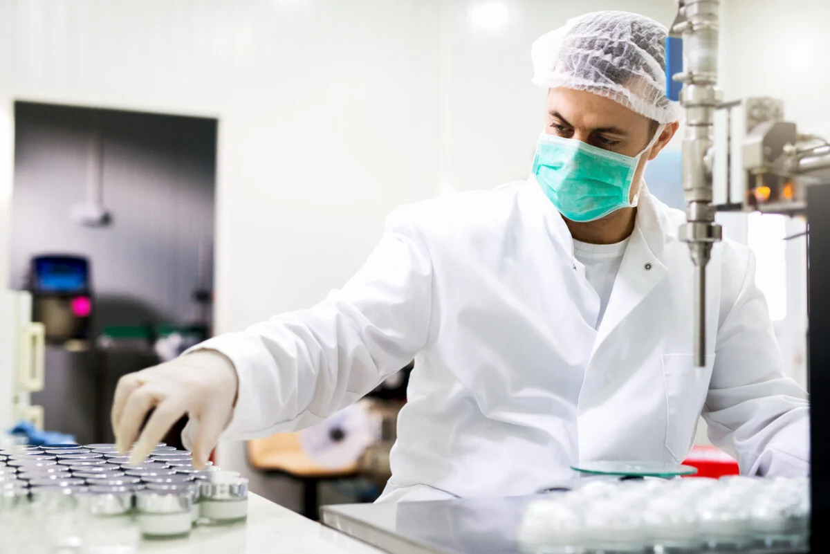 Technician in protective gear working on a pharmaceutical production line