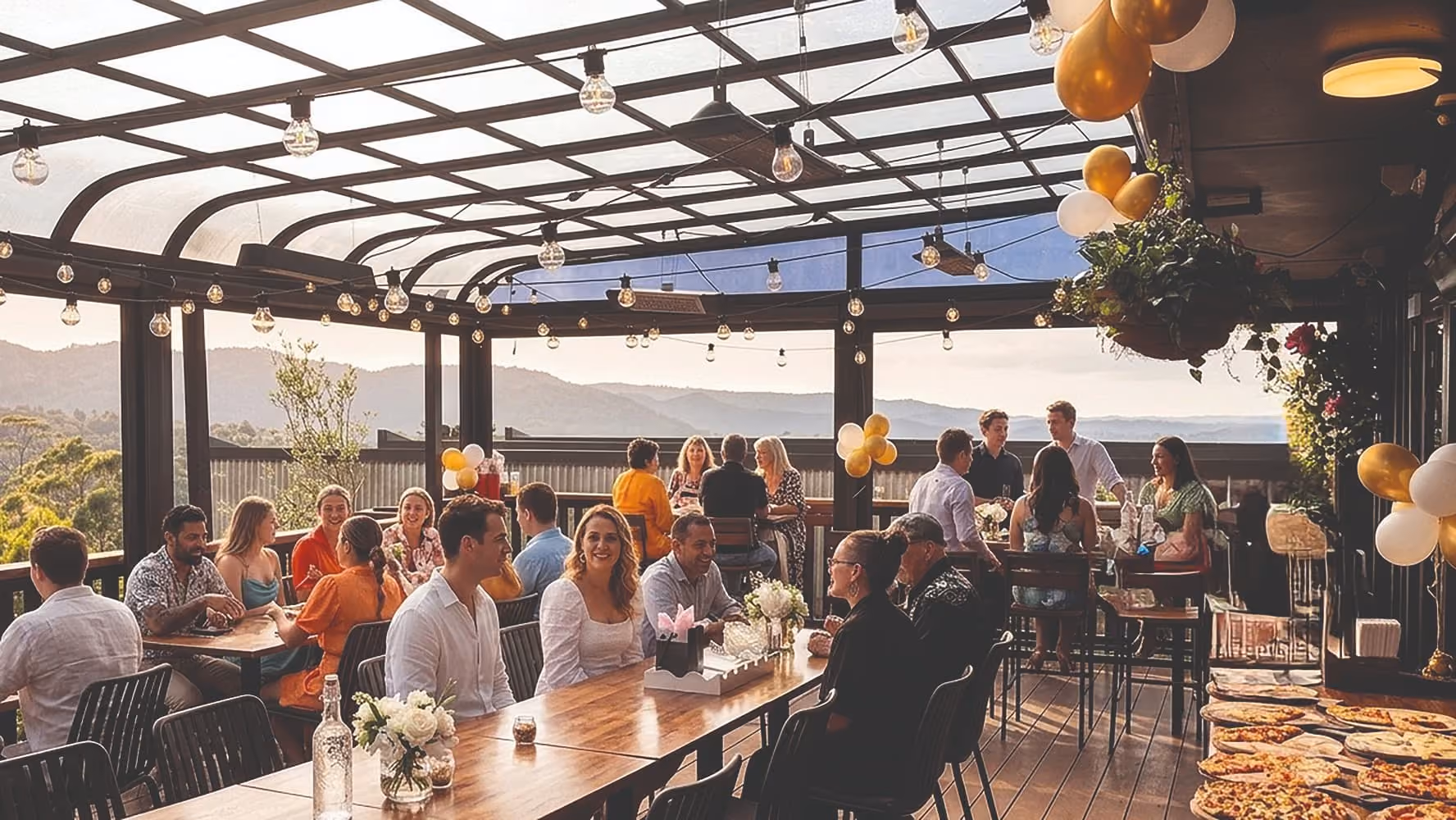 Guests enjoying a private function on the covered outdoor deck at The Olive Kitchen, with scenic views of the Waitakere Ranges.