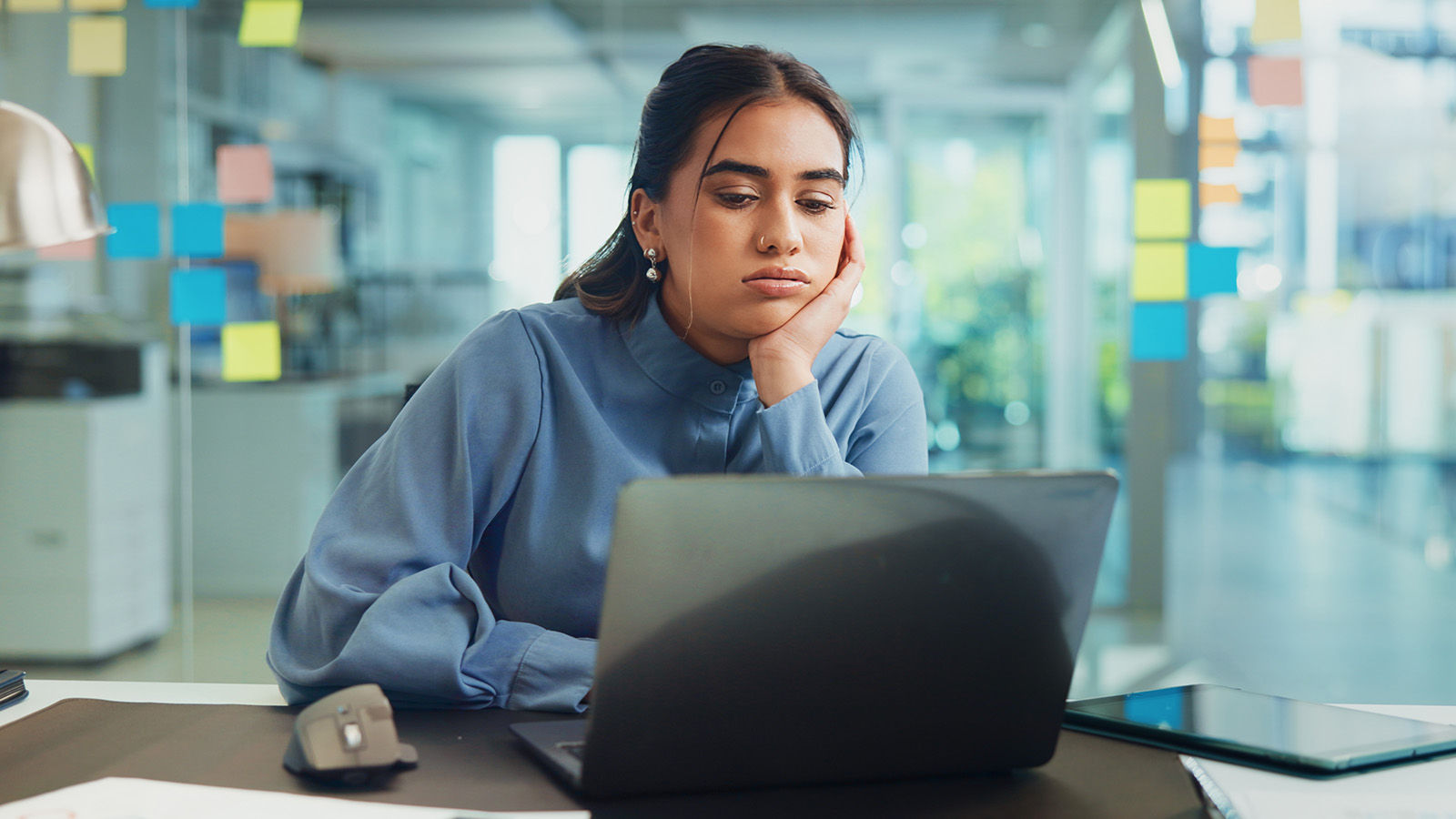 Frustrated office worker looking at her laptop in an open-plan office