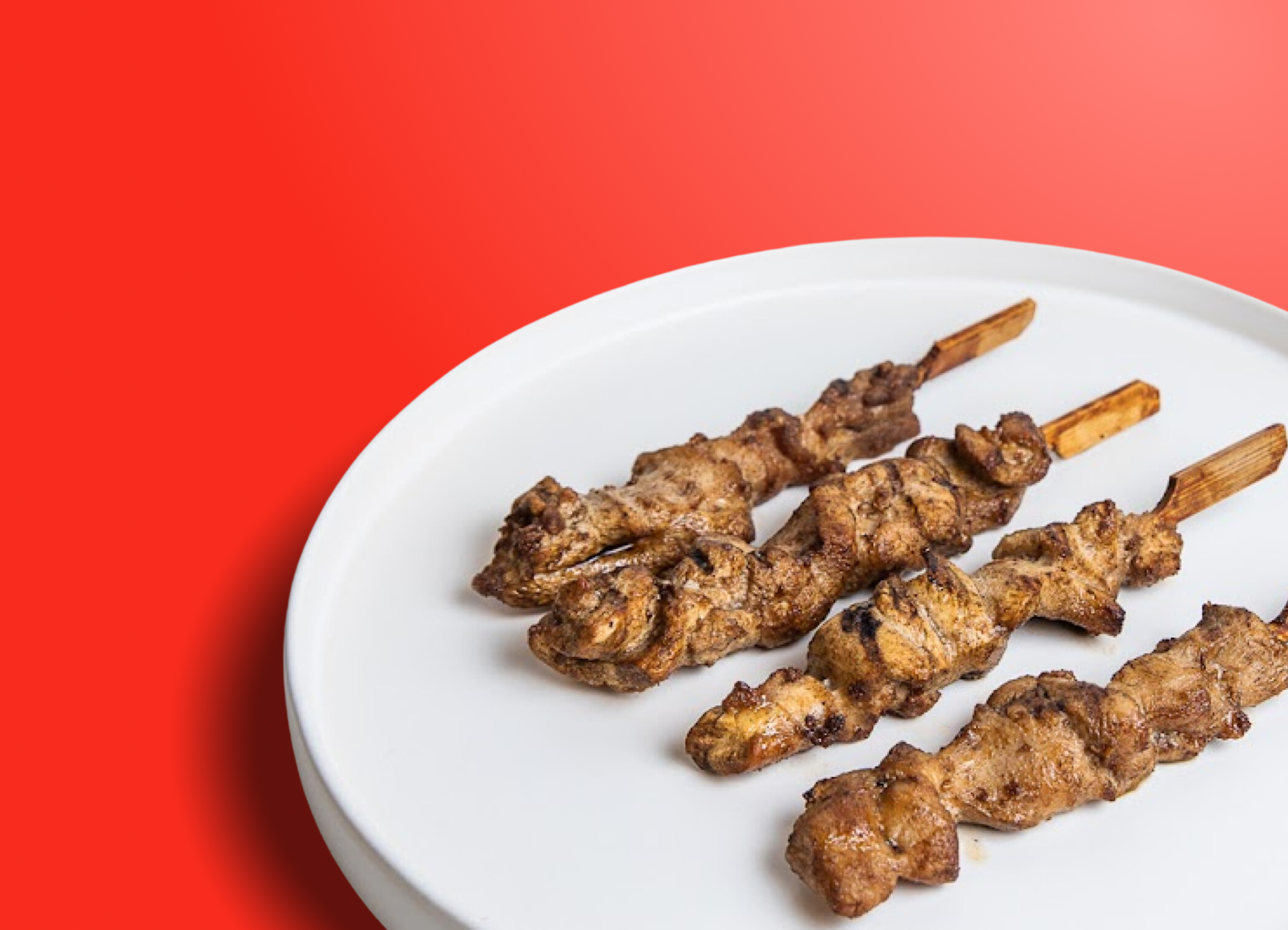 Hähnchenspieße von GoDumpling, angerichtet auf rotem Hintergrund