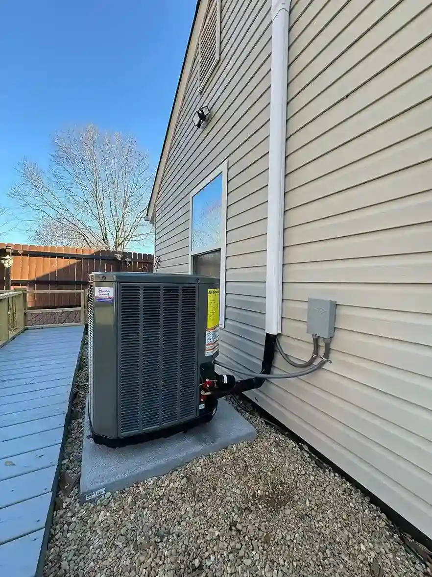 Air conditioning unit installed on side of house near wooden fence