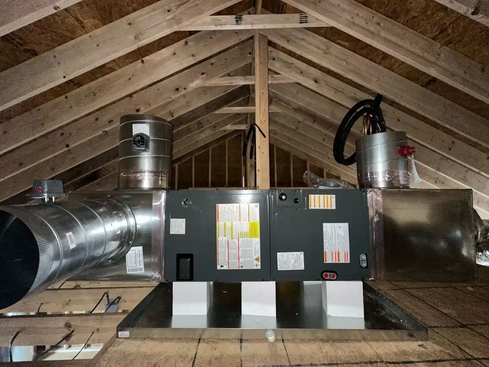 HVAC ventilation system installed in wooden attic with metal ductwork