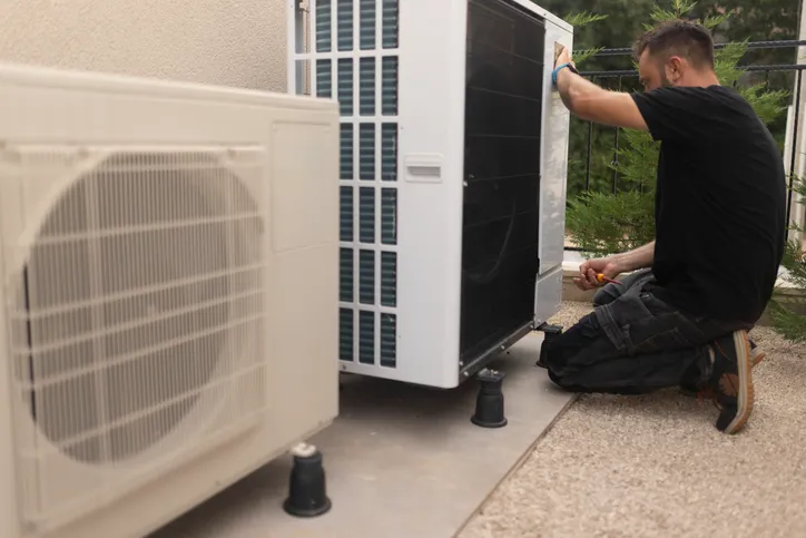 Technician installing or repairing an outdoor air conditioning unit