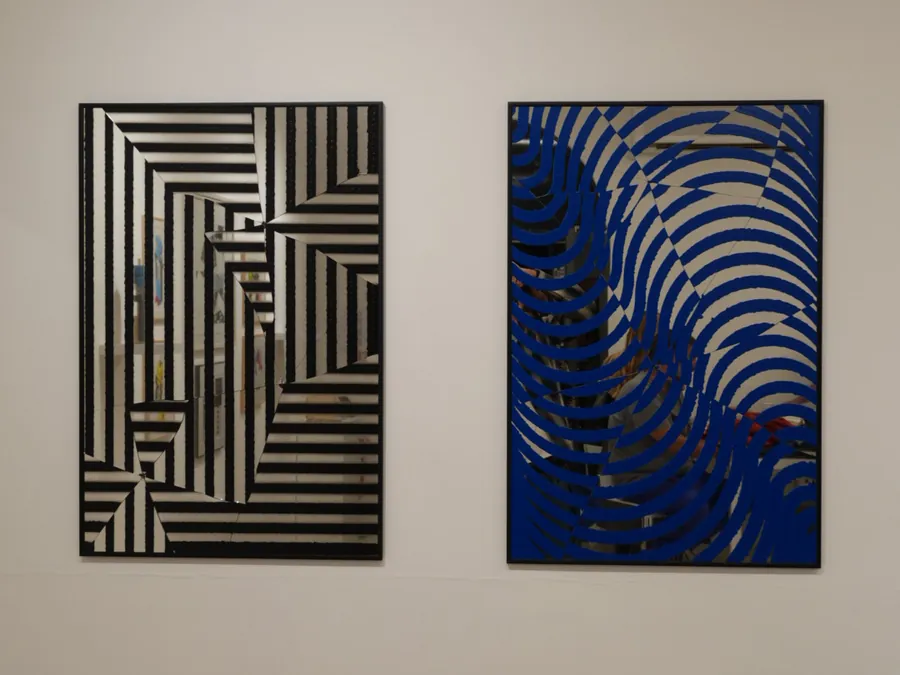 Due opere incorniciate in mostra a SpazioC21: strisce nere su fondo a specchio e onde blu