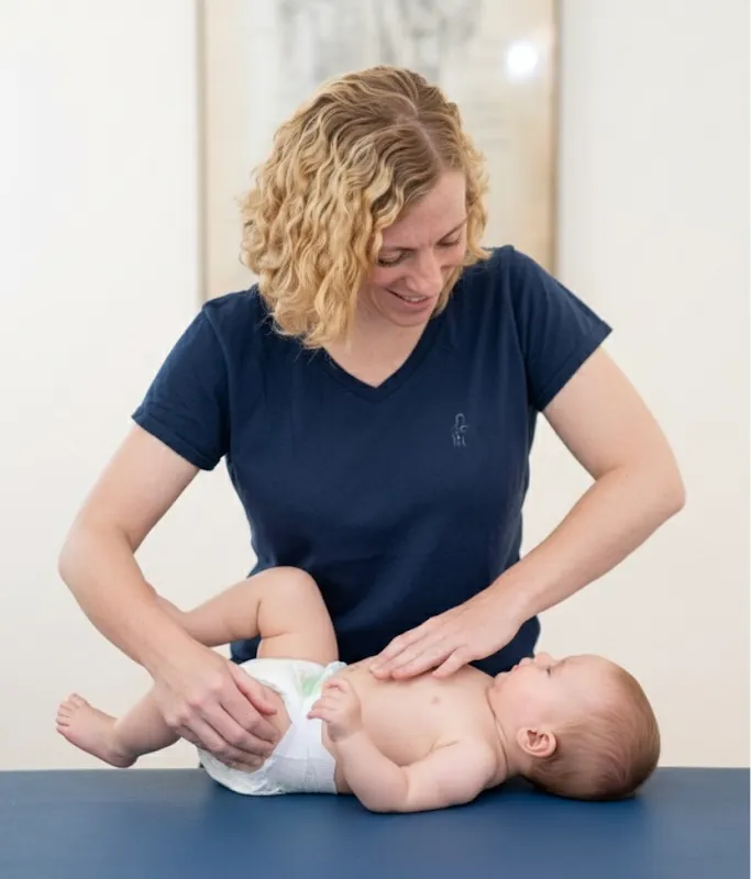Vojtabehandlung eines Kleinkindes durch blonde Kindertherapeutin