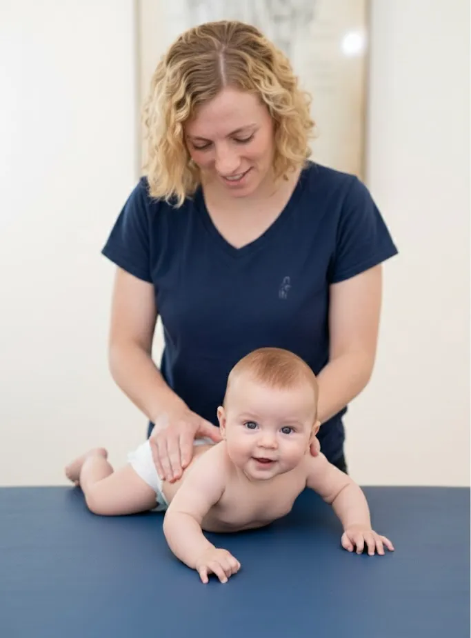 Vojtabehandlung eines Kleinkindes durch blonde Kindertherapeutin