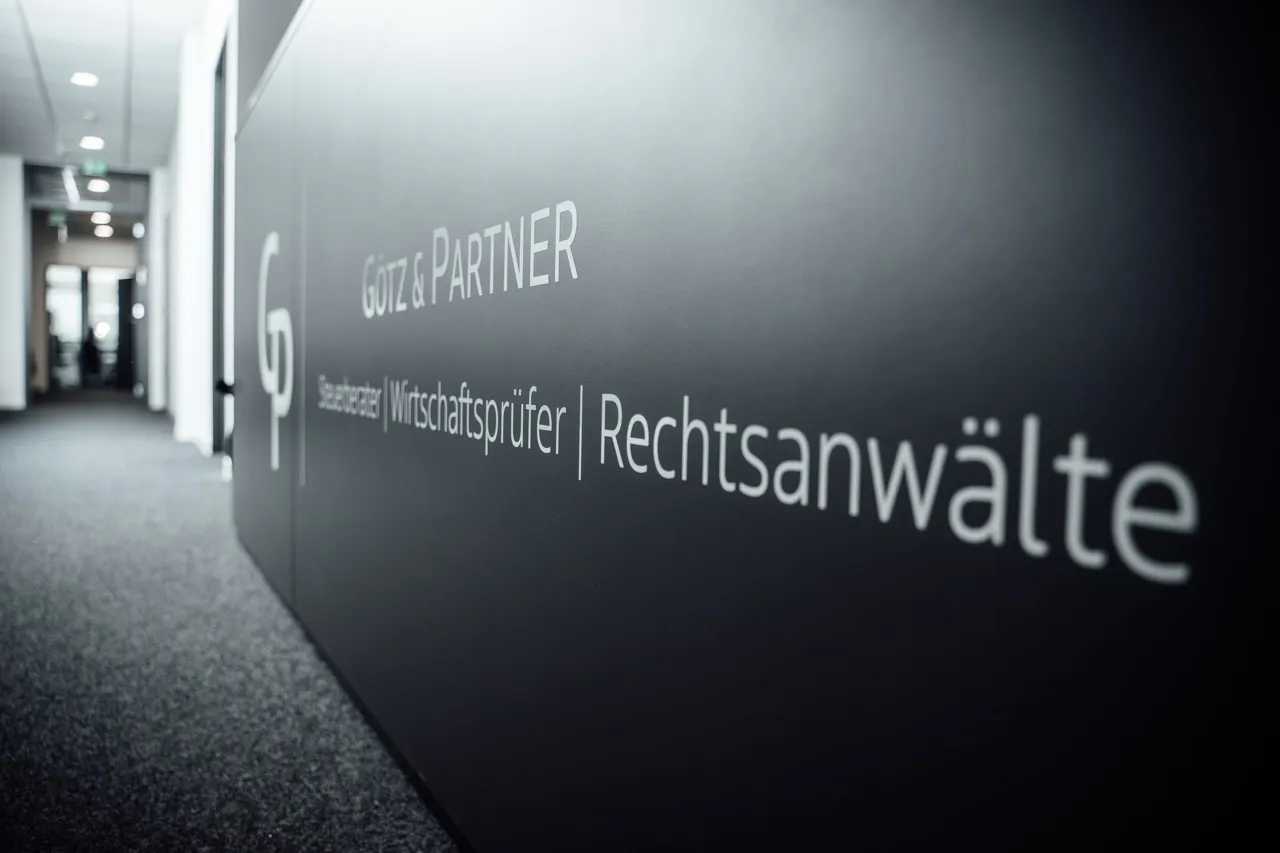 Innenaufnahme eines Raumes mit beleuchtetem „GP“-Logo an der Wand.