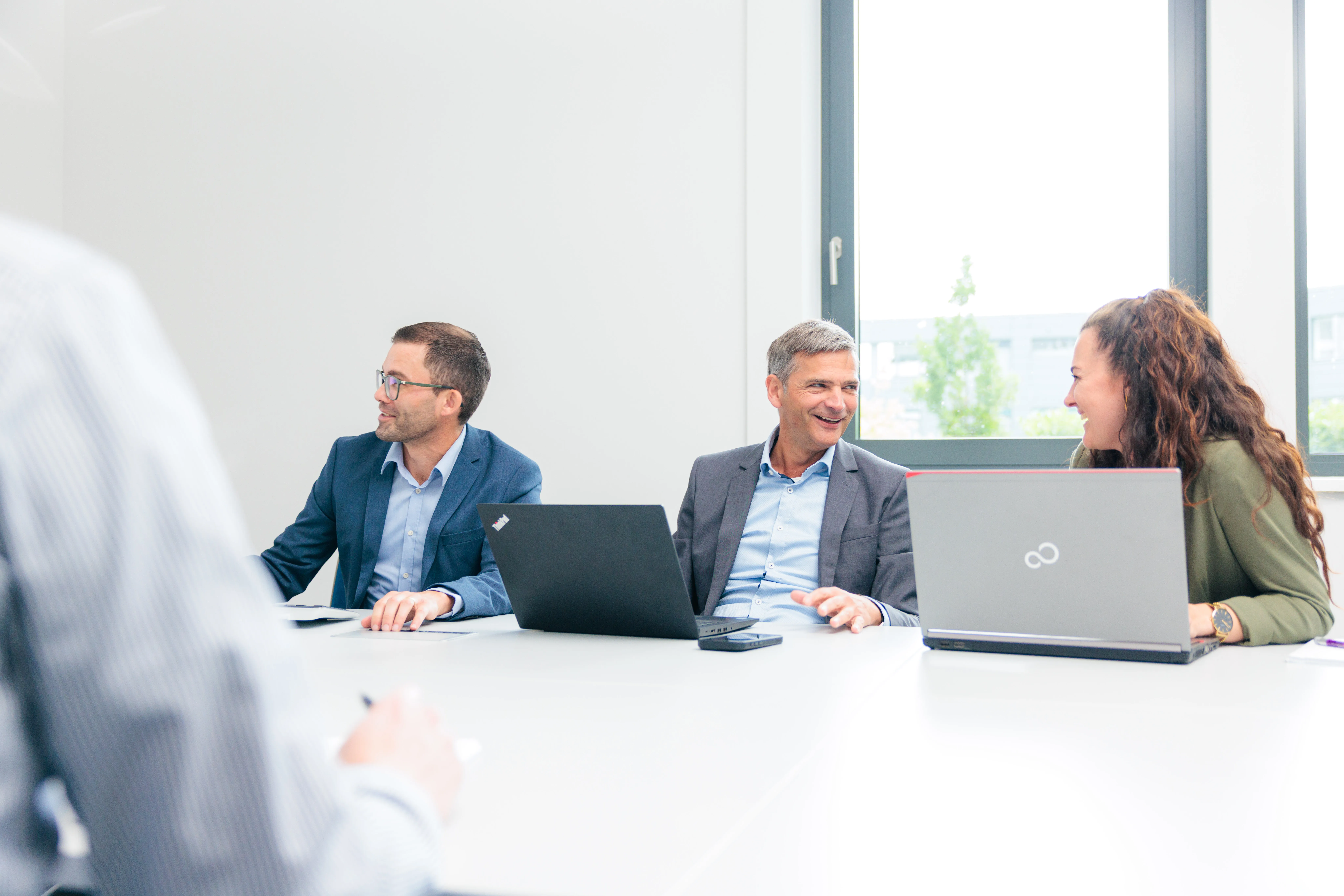 Mehrere Personen sitzen an einem Tisch und führen ein Gespräch im Büro.