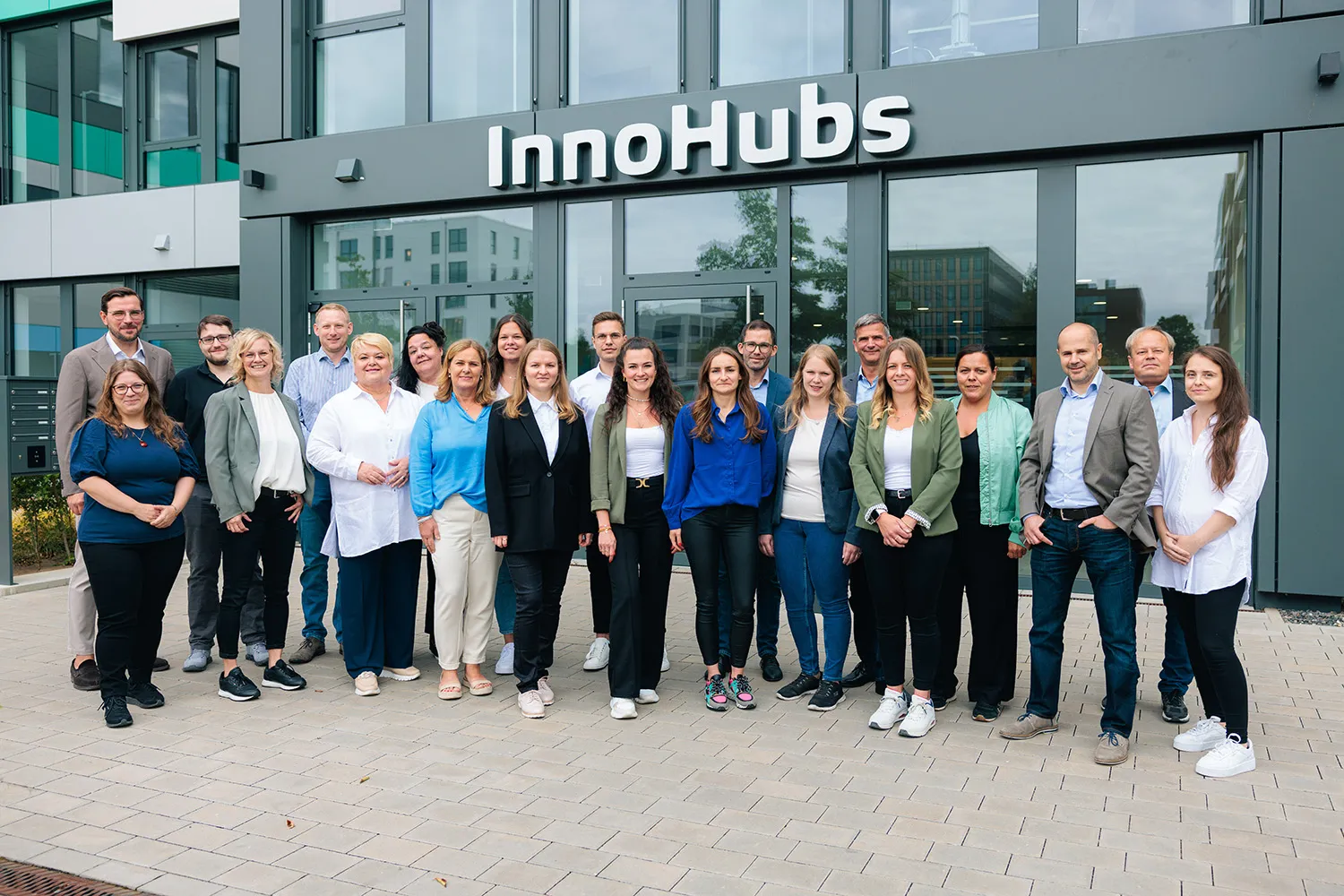 Mehrere Personen stehen gemeinsam vor einem Gebäude mit der Aufschrift „InnoHubs“.