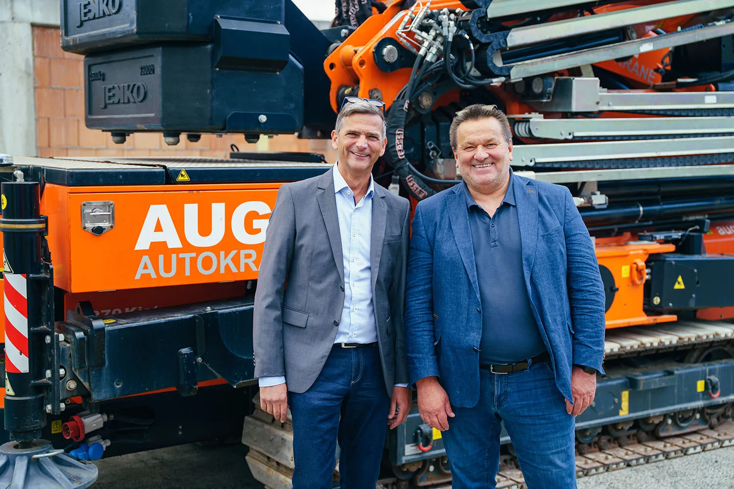 Zwei Männer stehen vor einer großen Baumaschine in einer Halle.