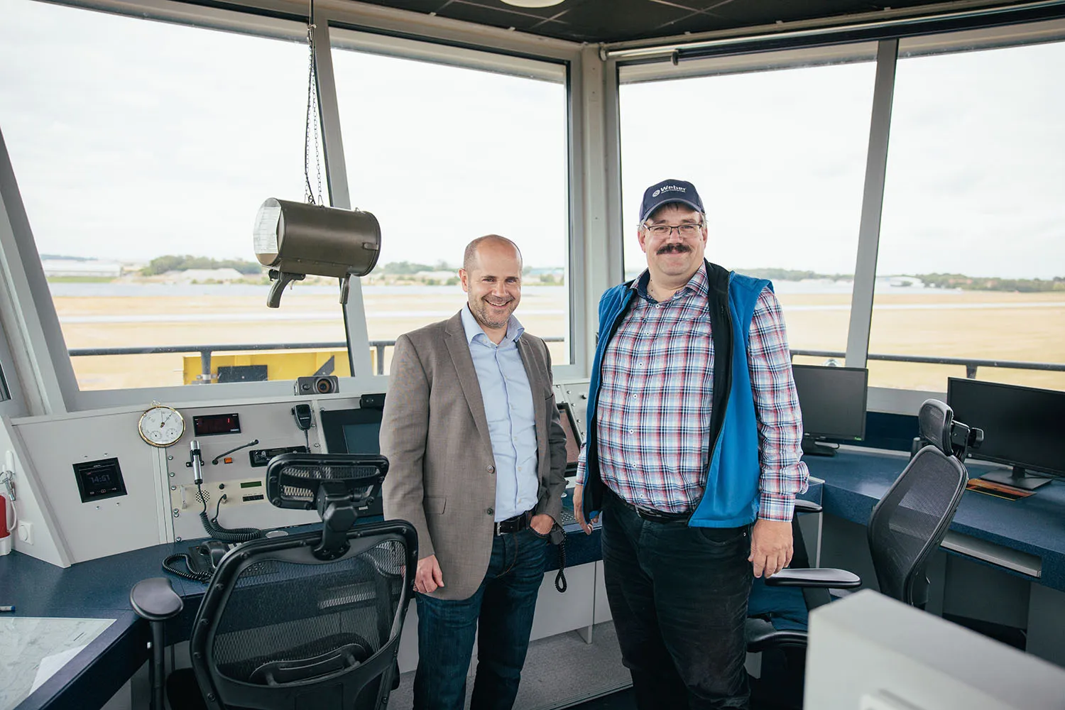 Zwei Männer stehen in einer Werkstatt oder Produktionshalle neben einer großen Maschine.