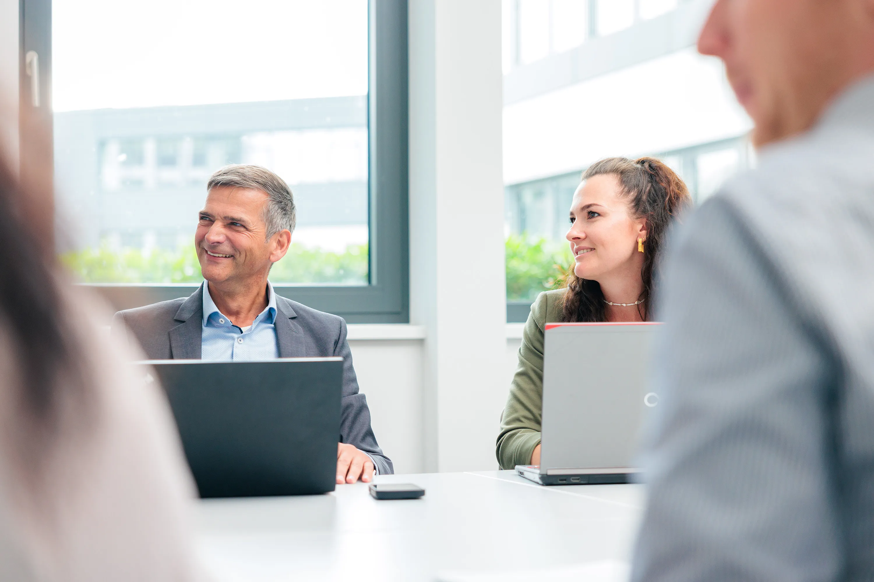 Mehrere Personen sitzen an einem Tisch und führen ein Gespräch in einem Besprechungsraum.