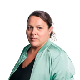 Porträt einer Frau mit dunklen Haaren, grünem Blazer und ernstem Gesichtsausdruck.