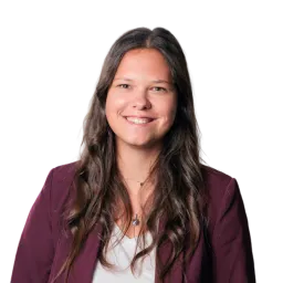 Porträt einer Frau mit langen dunklen Haaren, bordeauxfarbenem Blazer und hellem Oberteil.