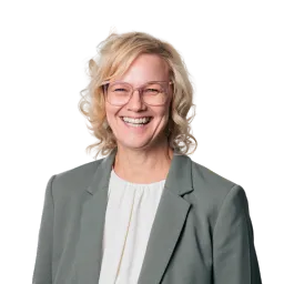 Porträt einer Frau mit kurzen blonden Haaren, hellem Blazer und freundlichem Lächeln.