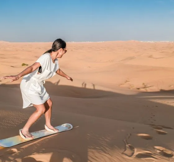 Session de sandboard dans les dunes de Dubaï pour une activité insolite pendant un séjour professionnel avec INÜI Collection.