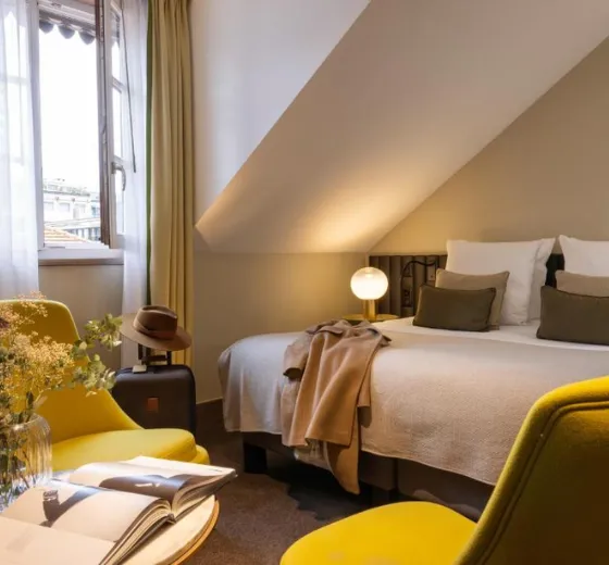 Lit double aux lignes épurées dans une chambre de l’Hôtel D. Genève pour un hébergement confortable avec INÜI Collection.