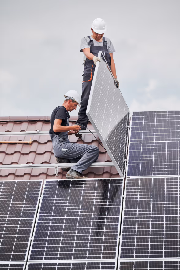 Handwerker montieren Solarmodule auf einem Dach.
