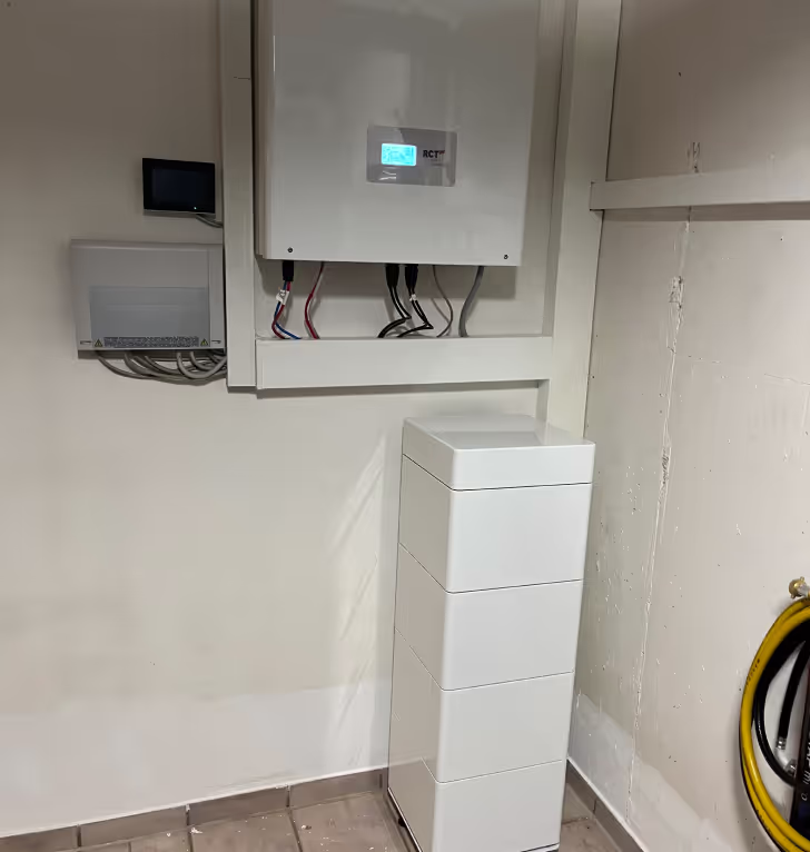 Weißer Batteriespeicher und Wechselrichter im Technikraum.