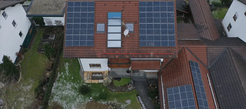 Solarmodule auf Hausdach mit mehreren Dachfenstern.