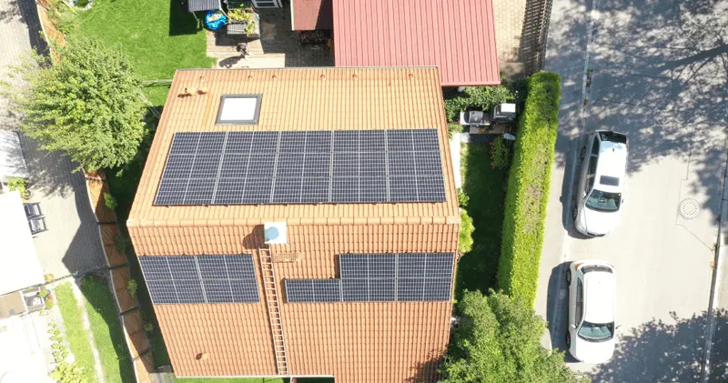 Hausdach mit Solarmodulen und Dachfenster.