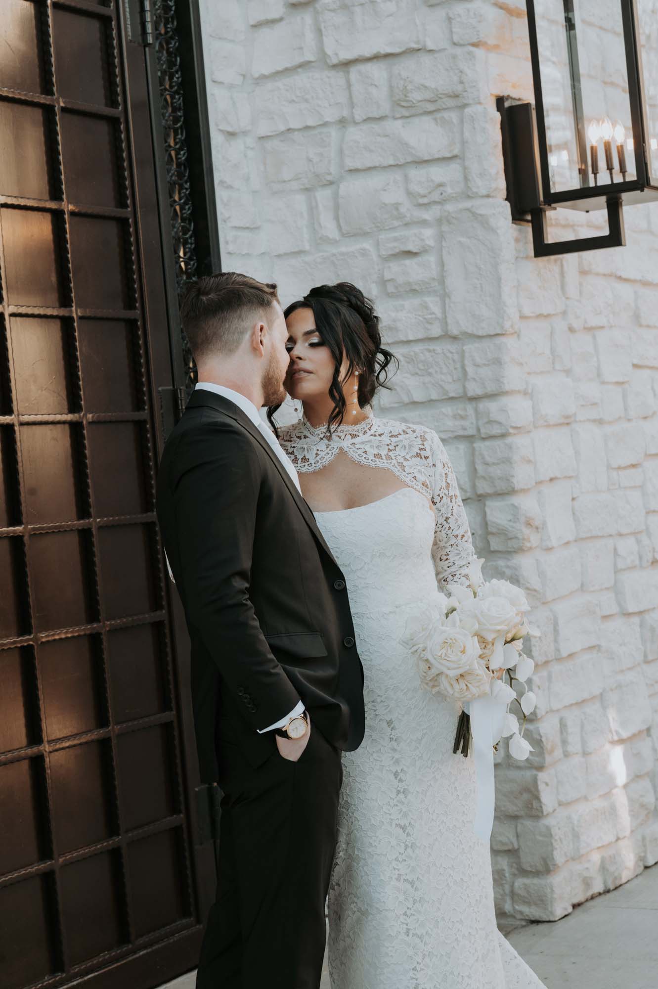 Bride and groom embrace near a venue entrance.