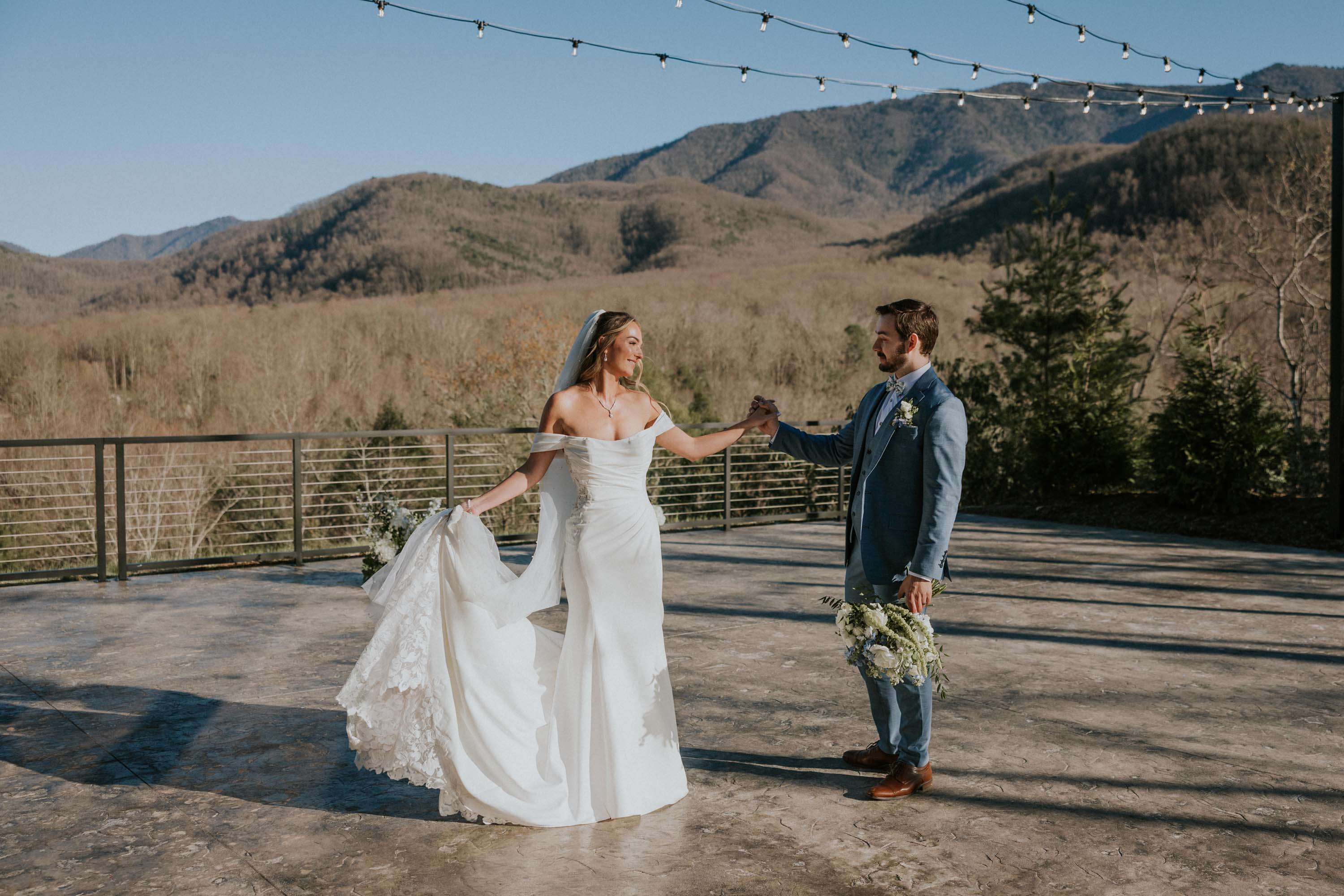 Bride and groom embrace on a terrace overlooking mountains at Trailhead Venues.