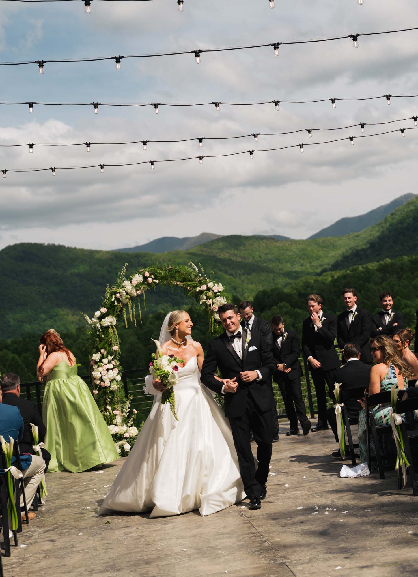 Bride and groom celebrate outdoors with wedding party against a mountain backdrop at Trailhead Venues.