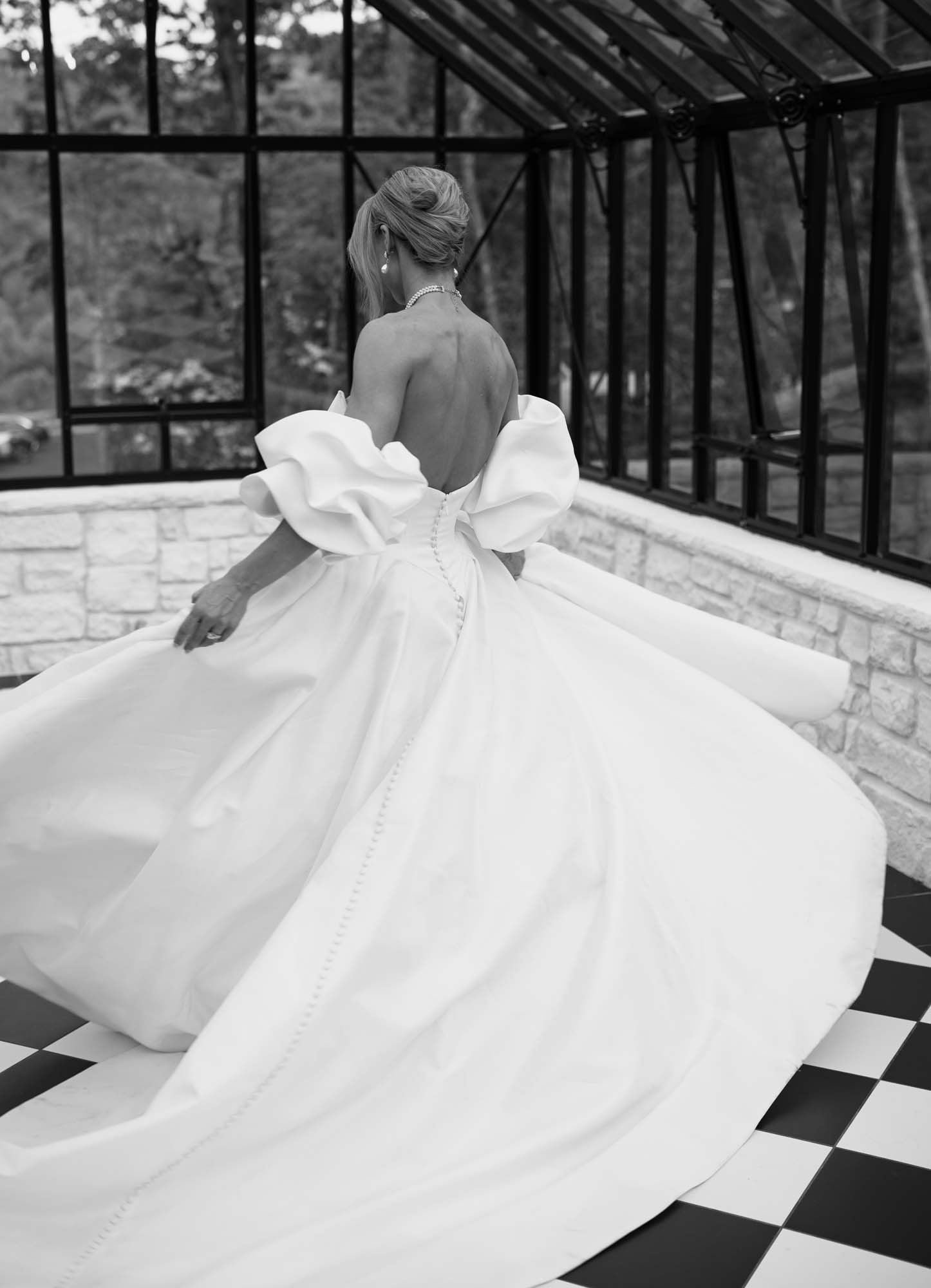 Bride in a voluminous gown stands before glass doors at Trailhead Venues.
