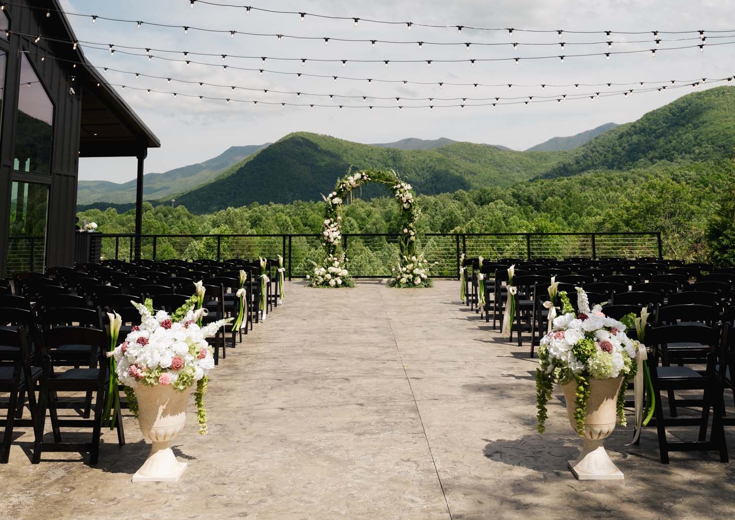Outdoor wedding aisle leading through trees toward a mountain backdrop at Trailhead Venues.