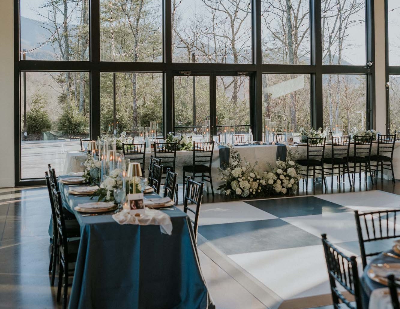 Elegant reception setup with large windows overlooking trees, perfect for a Smoky Mountains wedding.