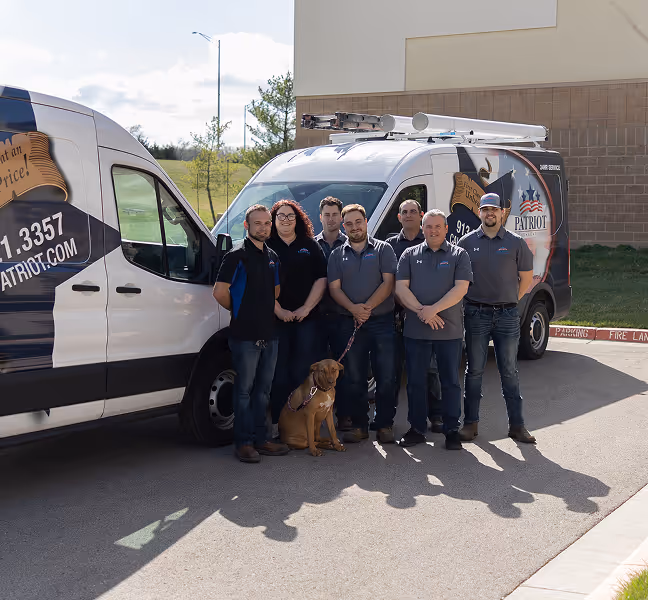 Patriot service team posing with work vans and friendly dog